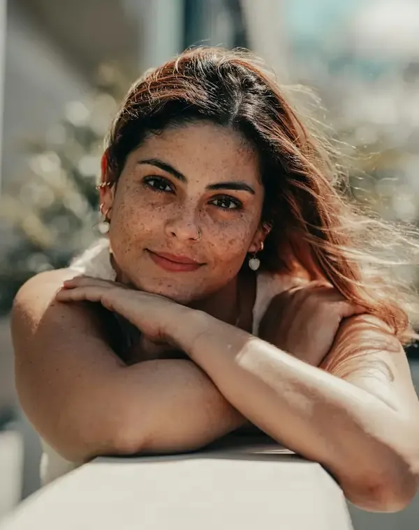 Mulher de cerca de 40 anos sorrindo, com luz natural
